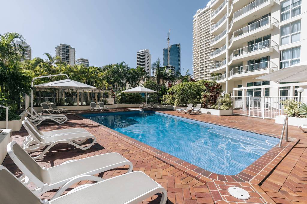 Poolside loungers and umbrellas with coastal skyline beyond